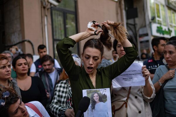 警察に拘束・暴行された女性の死を受けて行われた抗議デモで、イラン領事館前で髪の毛を切る女性（トルコ・イスタンブール、21日） - Sputnik 日本