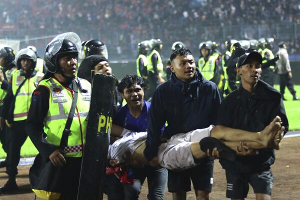 サッカースタジアムで試合後に発生した暴動で、負傷した男性を運ぶサポーターら（インドネシア・東ジャワ州、1日） - Sputnik 日本