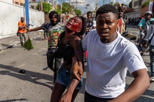 反政府デモの最中に負傷した女性を介抱する男性（ハイチ・ポルトープランス、10日） - Sputnik 日本