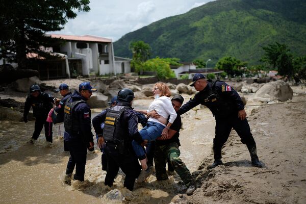 冠水した道路で女性が渡るのを手伝う警察（ベネズエラ・エル・カスターニョ、18日） - Sputnik 日本
