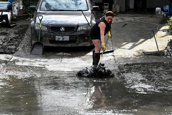 洪水被害を受けた自宅の敷地から泥を掃く女性（オーストラリア・メルボルン郊外、15日） - Sputnik 日本