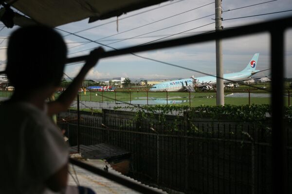 マクタン・セブ国際空港でオーバーランし、破損した大韓航空機を眺める少年（フィリピン・マクタン島、24日） - Sputnik 日本