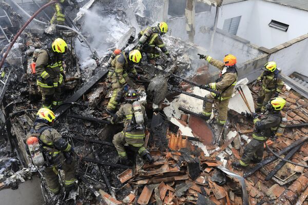 小型飛行機の墜落現場となった民家の屋根で作業する消防士たち（コロンビア・メデジン、21日） - Sputnik 日本