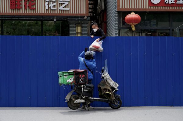 5月11日、中国・北京の新型コロナウイルス対策で封鎖された区域の住民に品物を渡す配達員 - Sputnik 日本