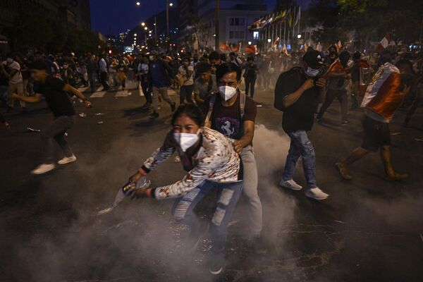 ペドロ・カスティジョ前大統領の釈放と議会の閉鎖を求める抗議デモで、警察が投げた催涙ガスから身を隠すペドカスティージョ前大統領の支持者（ペルー・リマ、11日） - Sputnik 日本