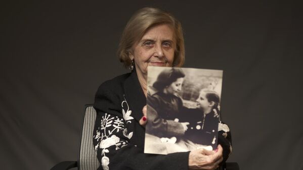 アウシュビッツ収容所に収容され、生き延びた母親と自身幼い頃の写真を手にとるポーランドのトバ・フリードマンさん（当時82）。写真は世界ユダヤ人会議提供（米ニューヨーク、2019年12月） - Sputnik 日本