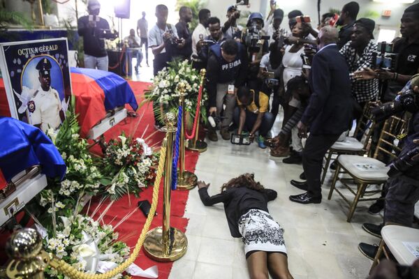 警察学校で行われた通夜の際、殉職した警官3人を納めた棺の横で横たわる女性（ハイチ・ポルトープランス、31日） - Sputnik 日本
