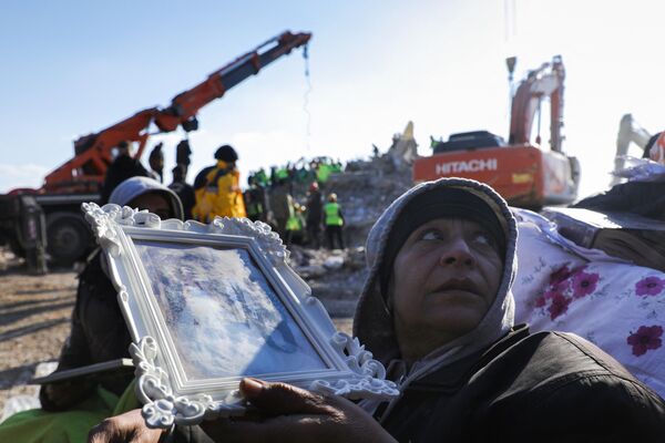 写真を持った男性と倒壊した建物の中から生存者を探す救助隊、トルコ南部ヌルダギ - Sputnik 日本