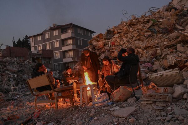 地震で倒壊した建物のそばで暖を取る人々（トルコ・ハタイ、14日） - Sputnik 日本