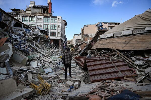 地震で倒壊した建物の間を歩く男性 - Sputnik 日本