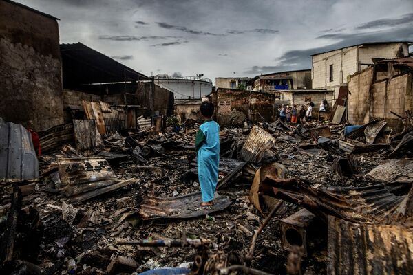国営石油会社プルタミナの燃料貯蔵所で起きた火災の後、焼失した家の跡に立つ少年（インドネシア・ジャカルタ、4日） - Sputnik 日本