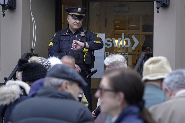 シリコンバレー銀行の支店の外で開店を待つ顧客が列を作る中、腕時計に目をやる警察官（マサチューセッツ州ウェルズリー、13日） - Sputnik 日本