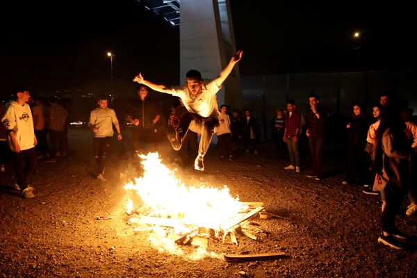 イラン暦の元旦「ノウルーズ」に先立ち行われた火祭り「チャハールシャンベ・スーリー」で、たき火を飛び越える男性（イラン・テヘラン、14日） - Sputnik 日本