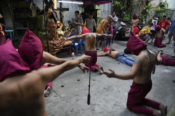 儀式の一環でフードをかぶって祈りをささげる鞭打苦行者たち（フィリピン・マンダルヨン、6日） - Sputnik 日本
