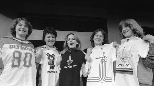 ドイツ・シュトゥットガルト近郊の衣料品工場で、ドイツ語圏向けに生産しているモスクワオリンピックのエンブレムが入った5種類のTシャツを掲げる女性たち（1980年2月撮影） - Sputnik 日本
