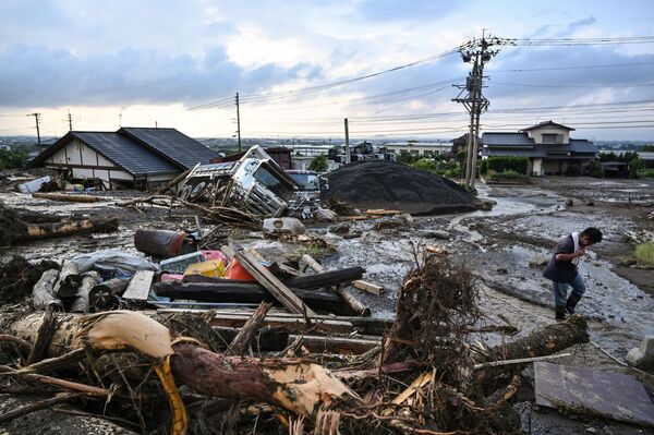 九州地方を襲った豪雨の後、瓦礫で埋め尽くされた通りを歩く男性（日本・福岡県久留米市、10日） - Sputnik 日本