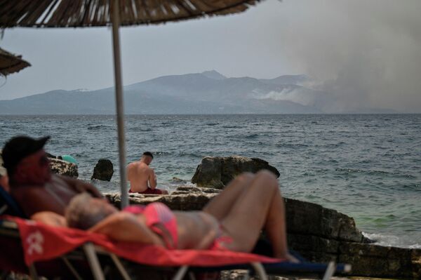 煙が立ち上る中で日光浴する人々（ギリシャ北西部コルフ島サランダ近郊） - Sputnik 日本