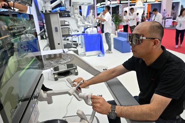 世界ロボット大会で、手術用のロボットアームを試す来場者（北京、16日） - Sputnik 日本