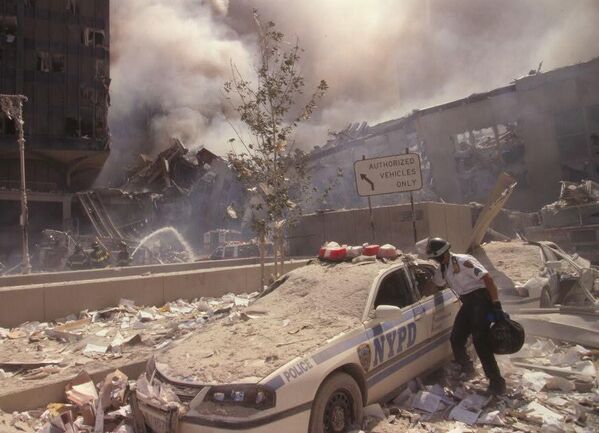 瓦礫に覆われたニューヨーク市警察の車に手を入れる救助隊員（9月11日） - Sputnik 日本