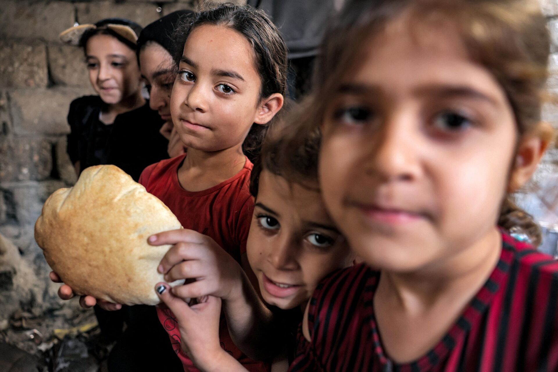 Дети с буханкой свежеиспеченного в глиняной печи хлеба в доме в Хан-Юнисе на юге сектора Газа - Sputnik 日本, 1920, 25.12.2023