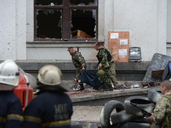 民兵がルガンスクの行政庁舎への空爆で死亡した男性の遺体を運ぶ様子。 民兵がルガンスクの行政庁舎への空爆で死亡した男性の遺体を運ぶ様子。 - Sputnik 日本