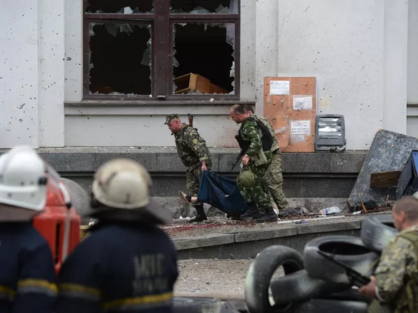 民兵がルガンスクの行政庁舎への空爆で死亡した男性の遺体を運ぶ様子。 - Sputnik 日本