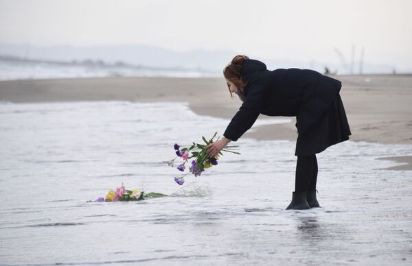 津波の犠牲者の追悼のため水に花を投げ入れる女性 - Sputnik 日本