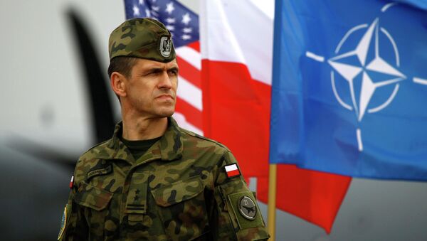 A Polish soldier stands near US and Poland's national flags and a NATO flag in Swidwin, northern west Poland, April 23, 2014 - Sputnik 日本