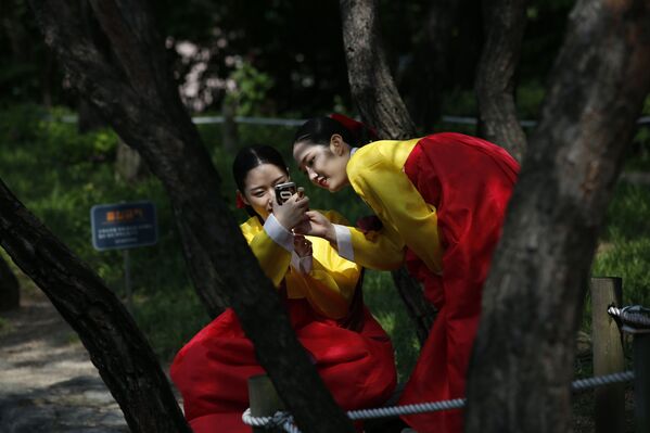 民族衣装を着た韓国の若い女性たち。スマートフォンをみている。 - Sputnik 日本