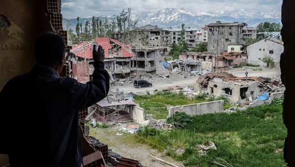 Мужчина на балконе перед разрушенными зданиями в ходе столкновений между турецкими войсками и курдскими военными в турецком городе Юксекова - Sputnik 日本
