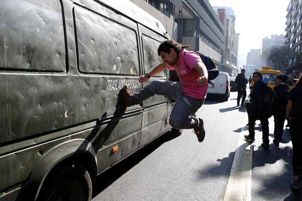 学生騒乱で警察の車を蹴飛ばすデモ参加者　チリの首都サンチャゴで。 - Sputnik 日本
