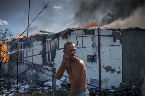 ウクライナ軍の空爆で火がついた家を消そうとする住民。ルガンスカヤ村で。 - Sputnik 日本