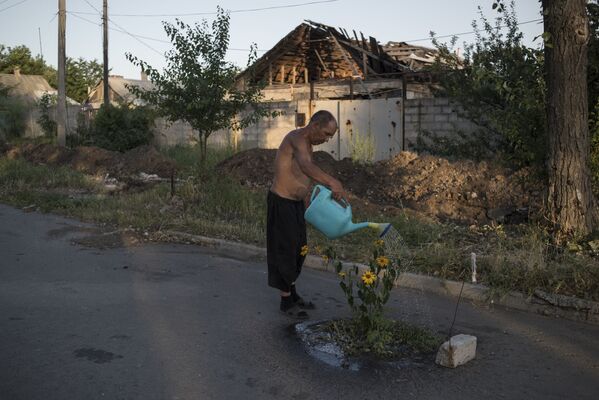 ヴィショーロエ村の通りに咲く花に水をやる男性　ドネツク州で。 - Sputnik 日本