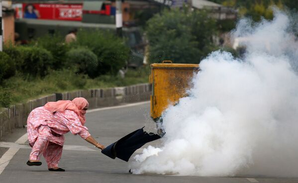 Женщина пытается прикрыть балон со слезотоカシミールでの殺人に抗議する人々に警察隊が投げた催涙ガスボンベを処理しようとする女性　インドのスリナガルで。чивым газом, брошенный полицией в протестующих против убийств в Кашмире, в индийском городе Сринагар - Sputnik 日本