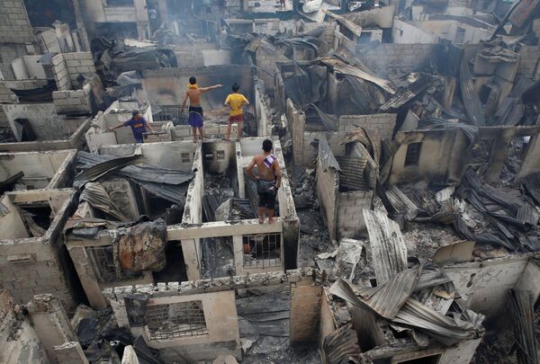 フィリピン、マンダリュイオンで燃え尽きた家の屋根の上に立つ住民 - Sputnik 日本