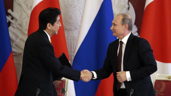 Japanese Prime Minister Shinzo Abe (L) shakes hands with Russian President Vladimir Putin - Sputnik 日本