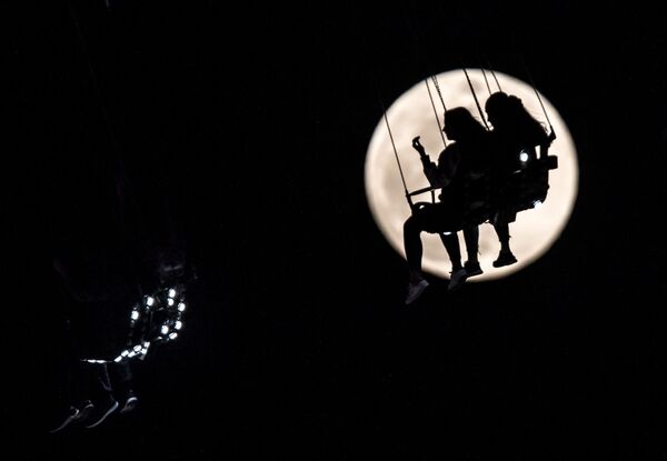 ドイツの都市フランクフルト・アム・マインの縁日で、満月をバックにメリーゴーランドに乗る - Sputnik 日本