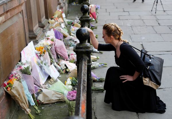 マンチェスターのテロの犠牲者に供えられた花のそばにしゃがみ込む女性 - Sputnik 日本