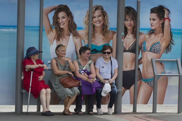 ビーチウェアの広告バナーのあるバス停でバスを待つ老齢の女性たち。マドリードにて - Sputnik 日本