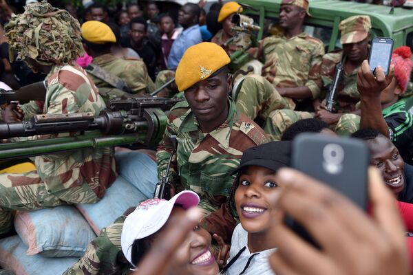 ジンバブエの首都ハラレで大統領辞任を求めるデモの際に軍の兵士と写真に収まる女性ら - Sputnik 日本