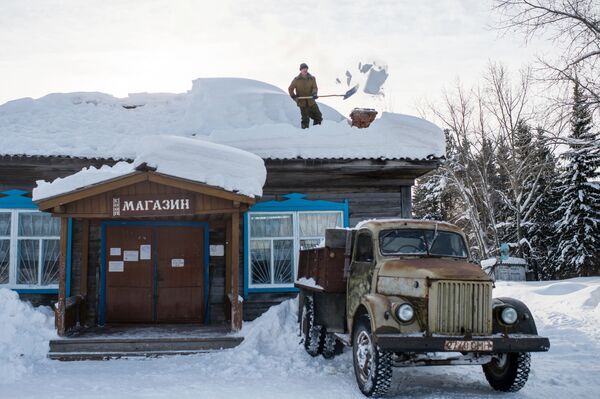 村で商店の屋根の雪かきをする男性 - Sputnik 日本
