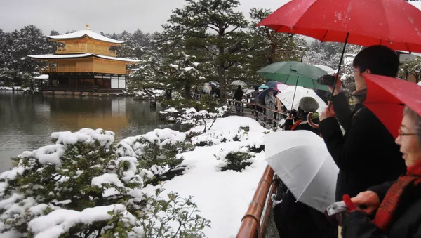 Tourists look at the snow covered Kinkakuji, golden pavilion, at Rokuonji Temple in Kyoto, western Japan on February 14, 2014 - Sputnik 日本