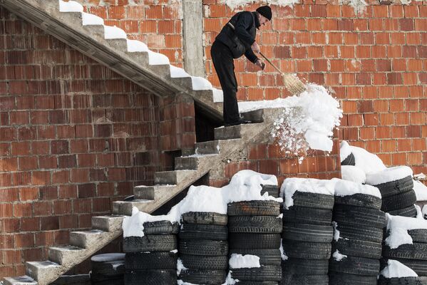 セルビアのプリシュティナにあるムラモル村で、建物の階段の雪かきをする男性 - Sputnik 日本