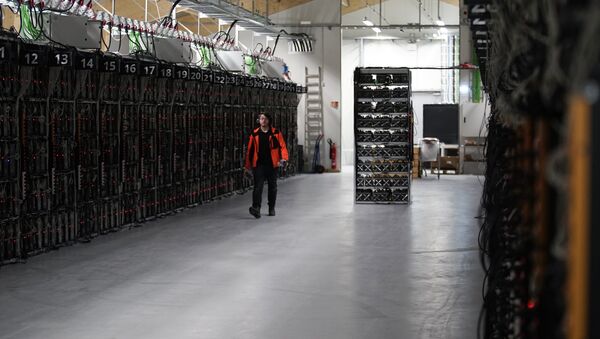 In this photo taken on Jan. 17, 2018, a worker walks along a row of computer rigs that run around the clock 'mining' bitcoin inside the Genesis Mining cryptocurrency mine in Keflavik, Iceland - Sputnik 日本