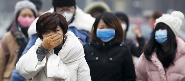 A woman uses her hand to cover her face from pollutants as people walk along a street on a polluted day in Beijing, Tuesday, Dec. 8, 2015. - Sputnik 日本