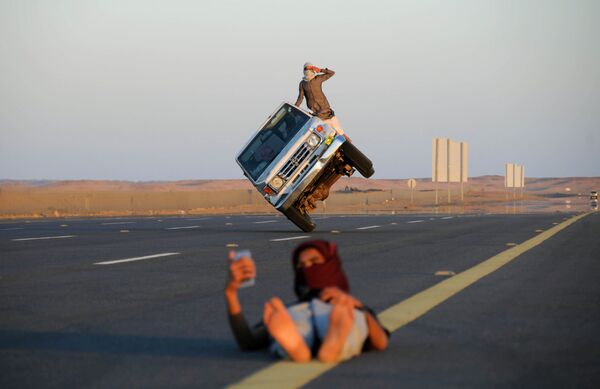 車を背景にセルフィーする人　その車で曲芸する若者　サウジアラビア - Sputnik 日本