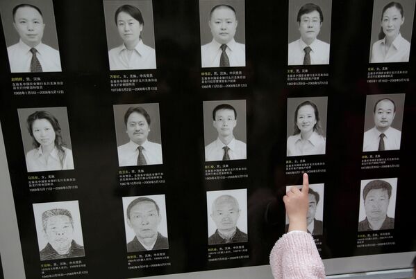 ２００８年の四川大地震時の犠牲者らの肖像が刻まれた追悼のプレートを見る少女 - Sputnik 日本