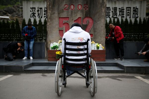 地震の犠牲者らの記念碑の前で悲しみに暮れる、２００８年の四川省での地震を体験した車椅子の男性 - Sputnik 日本