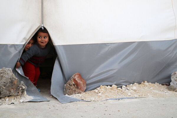 シリアにある仮設キャンプのテントから外を覗く子供たち - Sputnik 日本