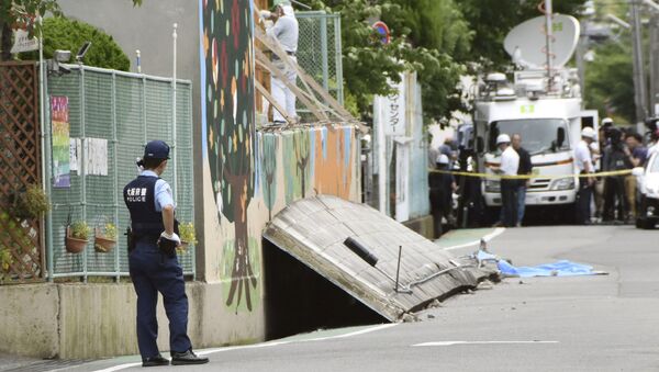 A police officer stands guard at the site where a girl was killed by fallen wall caused by an earthquake at an elementary school in Takatsuki, Osaka prefecture - Sputnik 日本